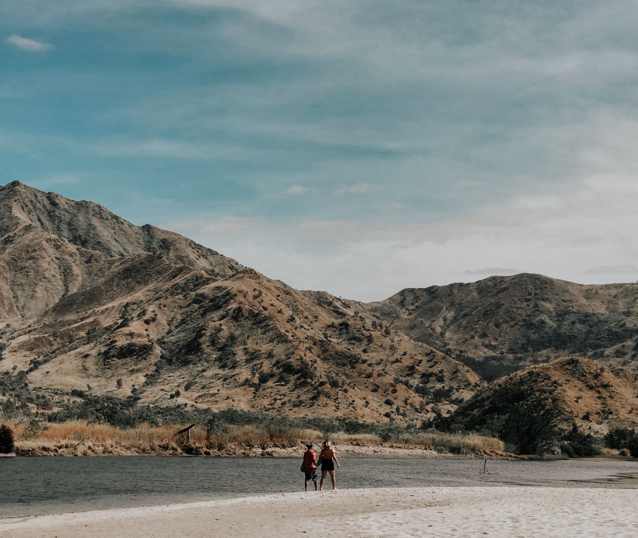 A couple hiking together in a beautiful mountainous landscape under a clear blue sky, enjoying an outdoor adventure