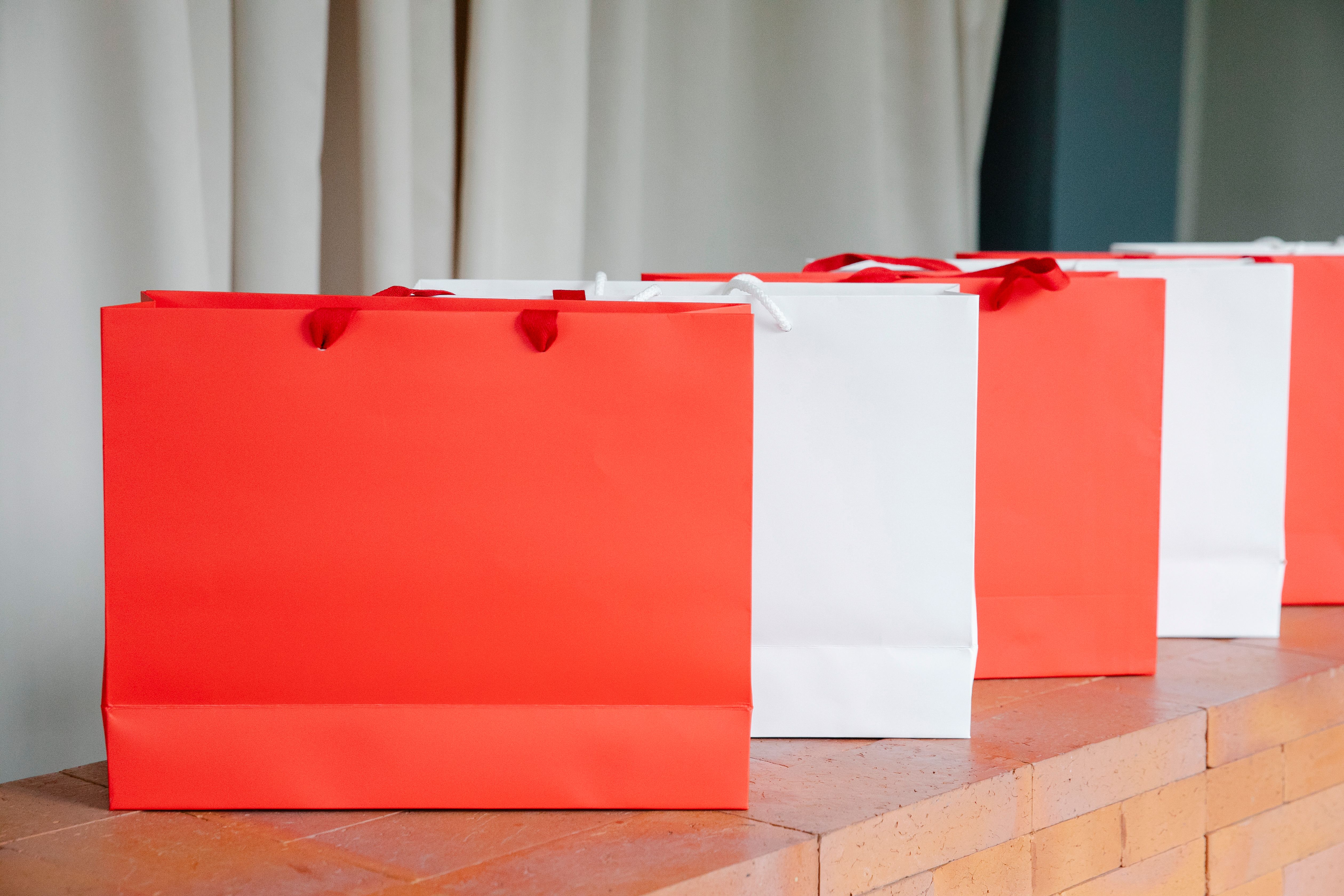 Set of red and white paper shopping bags, symbolizing material possessions and consumerism