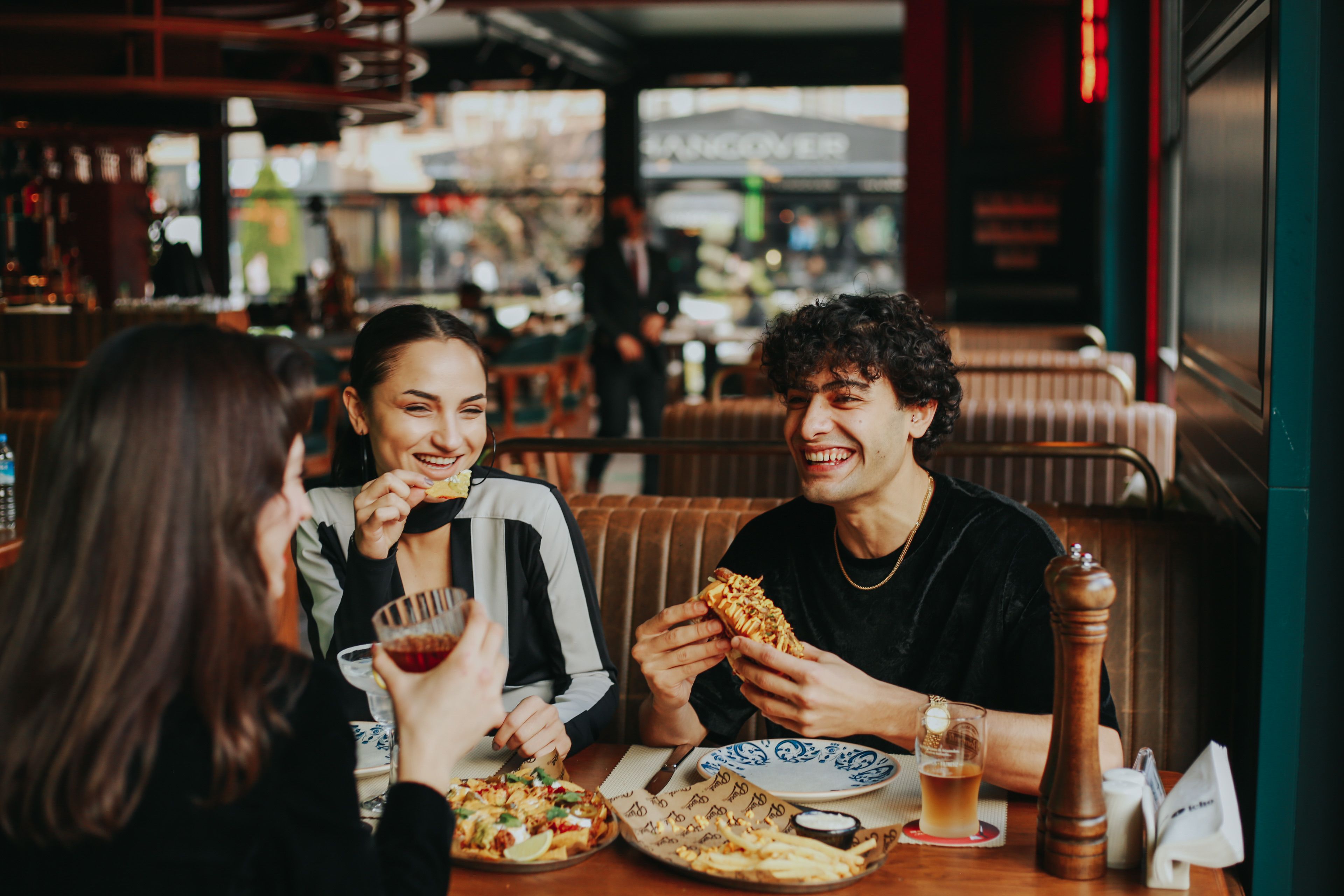 Group of friends laughing and eating at a restaurant, enjoying quality time together