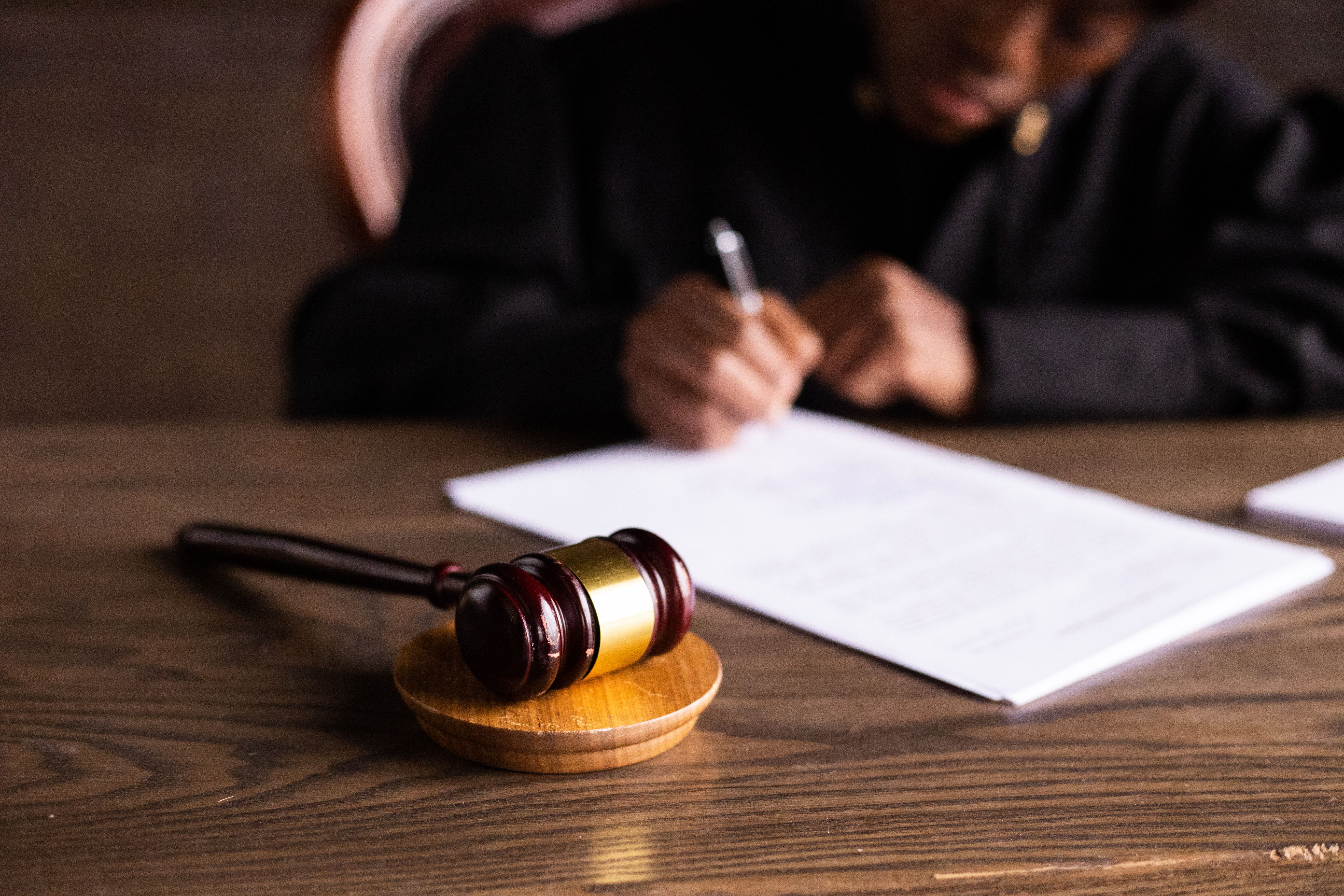 Judge signing court documents at a desk with a gavel, representing judicial rulings in complex litigation