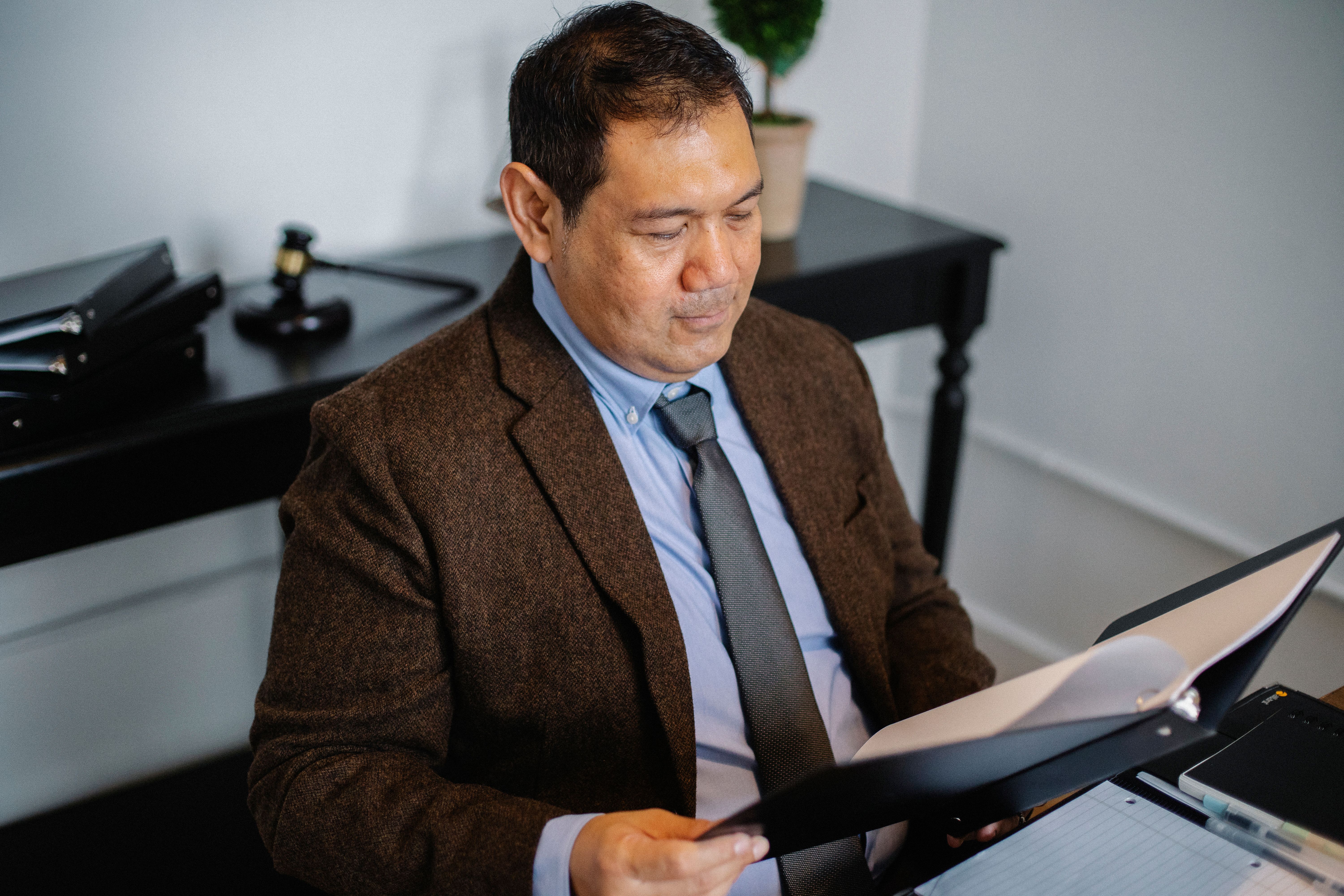 Lawyer in a suit reviewing a case report in a folder during the discovery phase of litigation
