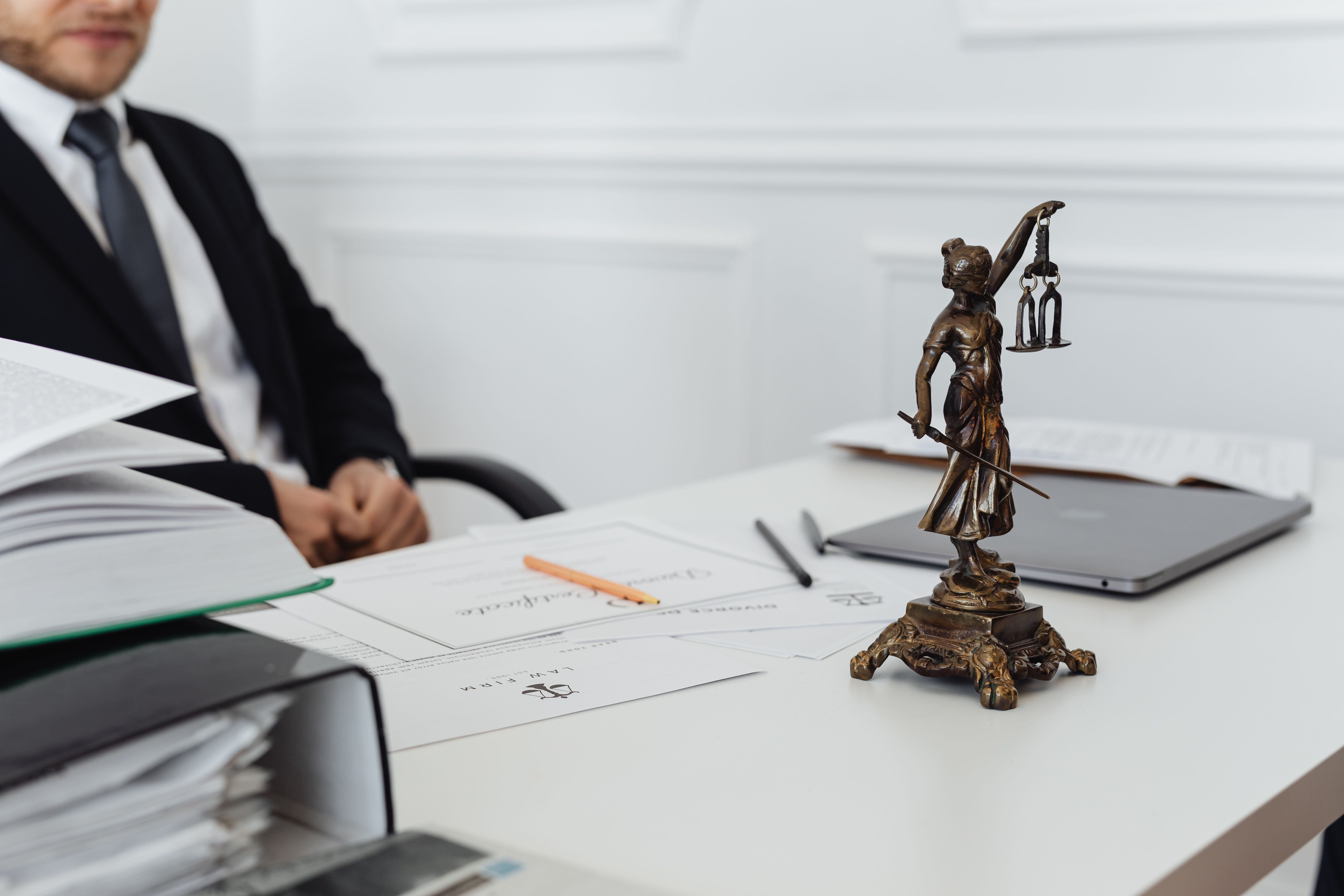Legal professional workspace with a Lady Justice statue, case files, and laptop representing litigation resolution