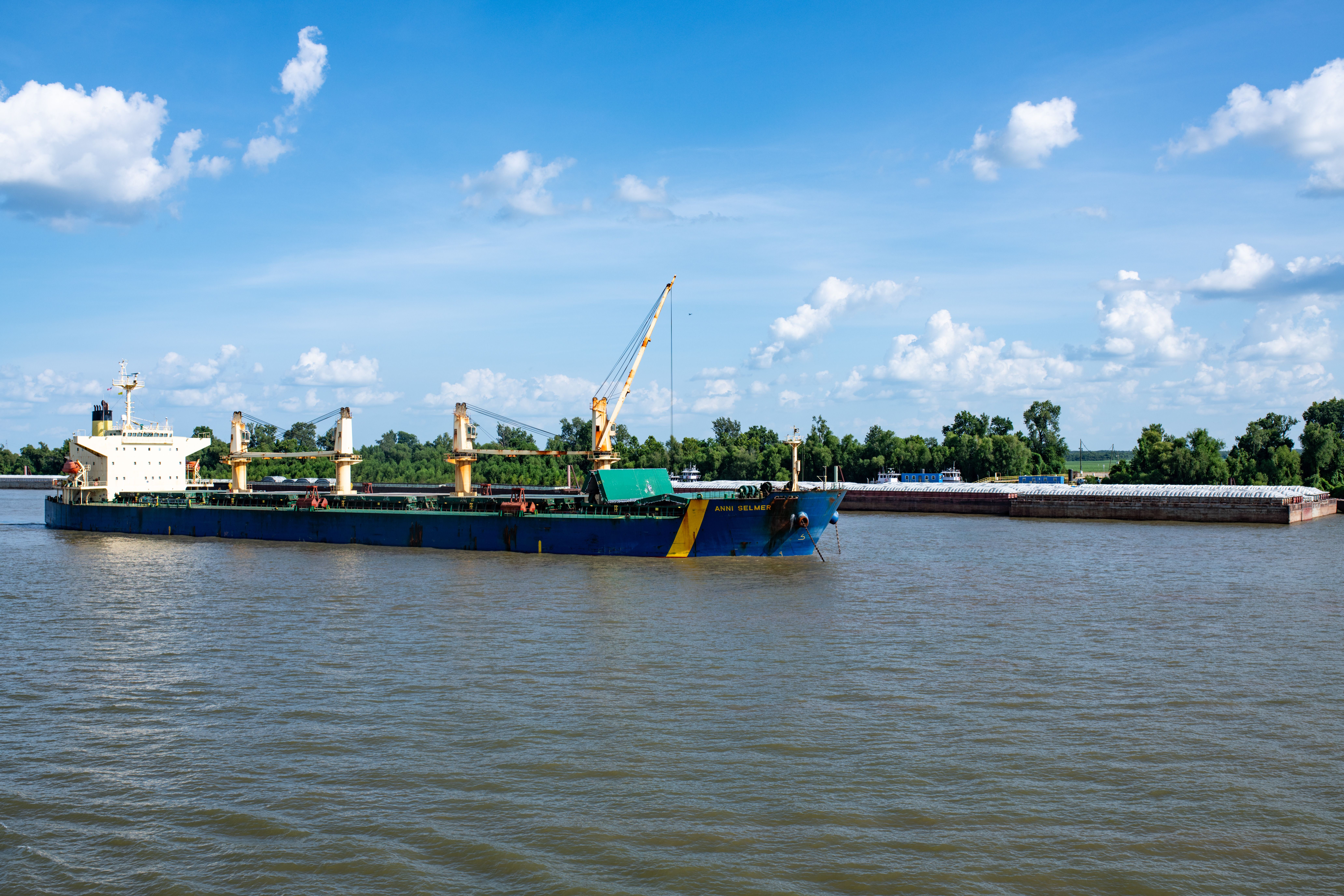 Cargo ship traveling along the Mekong River through green forest, representing river commerce and sustainable regional development.